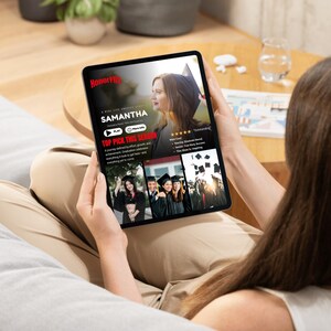 May include: A person holding a black tablet displaying a movie poster for "Samantha." The poster features a woman in a graduation cap. The tablet screen also shows images of graduates and the text "Top Pick This Season."