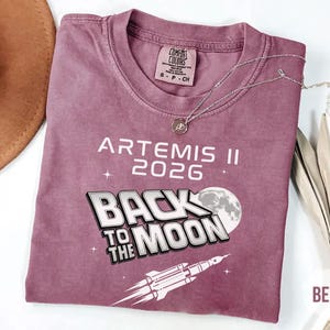 Berry Comfort Colors Artemis II 2026 shirt with white Back To The Moon graphic and rocket launch illustration