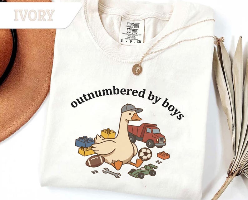 Ivory shirt with black text and cute goose surrounded by toys