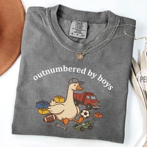 Pepper shirt with “outnumbered by boys” curved text and goose