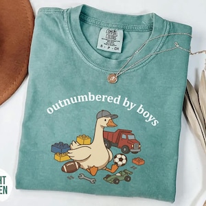 Light green shirt with cartoon goose and toy elements