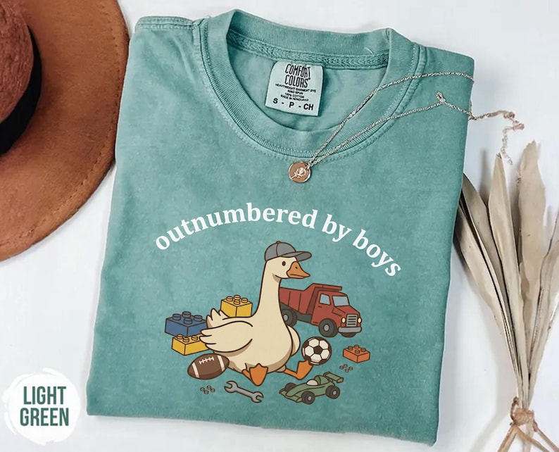 Light green shirt with cartoon goose and toy elements