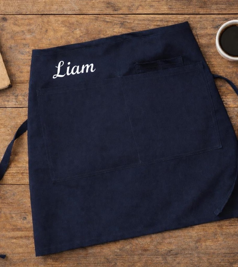 Op de afbeelding: Een set van drie keramische mokken met een gespikkelde, cr&egrave;mekleurige glazuur. Elke mok heeft een ander handgeschilderd ontwerp: een blauw en groen blad, een gele bloem en een rode bes. De mokken hebben een eenvoudige, afgeronde vorm.