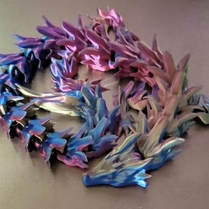 May include: A 3D-printed dragon sculpture in shades of blue, purple, and pink. The dragon is curled up, with intricate details on its scales and claws. The sculpture is approximately 12 inches long.