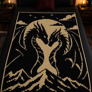 Puede incluir: Una manta de ganchillo rectangular con un diseño de alto contraste en negro y crema. El patrón muestra a dos dragones frente a frente ante una gran luna circular, con picos montañosos dentados y pequeñas estrellas en el cielo nocturno.