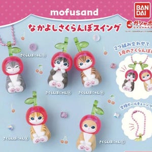 Pu&ograve; includere: Una collezione di figurine di gatti con cappelli a forma di ciliegia. Le figurine sono in vari colori, tra cui grigio, marrone e arancione, e sono alte circa 4,3 cm. L'immagine include testo giapponese e uno sfondo rosa.