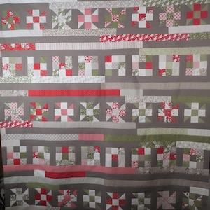 Peut inclure: Une courtepointe avec un fond gris, des bandes horizontales et des blocs dans des tons de rouge, rose, blanc et vert. Le motif intègre divers tissus à motifs floraux, rayés et unis disposés selon une disposition en forme de grille.