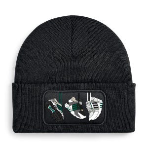 May include: A black knit beanie featuring a rectangular patch on the cuff. The patch displays a graphic illustration of three white, gray, and green athletic sneakers hanging by their laces against a dark gray background.