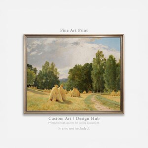 Puede incluir: Una impresión artística enmarcada de un paisaje rural. La obra de arte representa un campo con pacas de heno, un camino de tierra y árboles bajo un cielo nublado. La impresión incluye el texto "Fine Art Print" y "Custom Art | Design Hub".