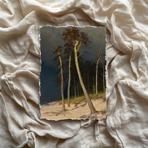 Puede incluir: Una impresión artística que presenta una pintura de paisaje de árboles altos en una playa arenosa bajo un cielo oscuro y tormentoso. La obra de arte tiene un borde rasgado y está colocada sobre un fondo de tela beige. Los colores de la pintura incluyen tonos de marrón, verde y azul.