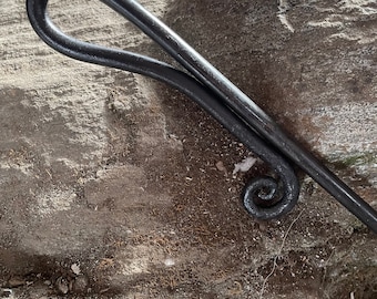 Puede incluir: Un atizador de chimenea de metal negro con un mango curvo y un detalle en espiral en el extremo.