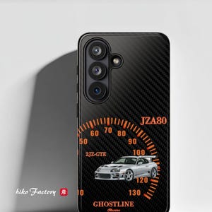 May include: Black phone case with a carbon fiber texture and an orange speedometer design. The design includes a silver car, the text "JZA80", "2JZ-GTE", and "GHOSTLINE". The brand name "hiko Factory" is also visible.