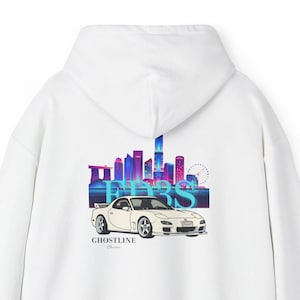 以下が含まれることがあります： 白いパーカー。白いスポーツカーと都市のスカイラインのグラフィックが特徴です。「FIERS」と「GHOSTLINE」の文字がスタイリッシュにデザインされています。デザインは青、紫、ピンクの色合いを使用しています。