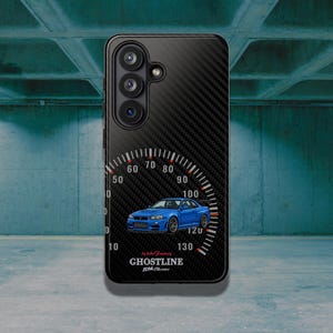 Pode incluir: Uma capa de telemóvel preta com textura de fibra de carbono com um gráfico de um carro desportivo azul centrado sobre um design de velocímetro branco. O texto GHOSTLINE JDM está impresso a branco por baixo do carro, com texto vermelho.