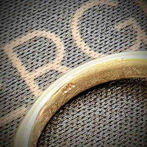 May include: A gold ring with a smooth, polished surface and a rounded band. The interior of the band features a small, stamped hallmark that reads 14K, indicating the metal purity. The ring is positioned against a dark, textured background.