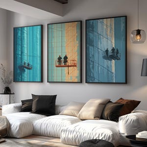 Puede incluir: Tres impresiones artísticas enmarcadas que representan a limpiadores de ventanas en rascacielos. La obra de arte presenta una paleta de colores de color turquesa, naranja y azul. Las impresiones se muestran encima de un sofá seccional blanco con cojines negros y beige.