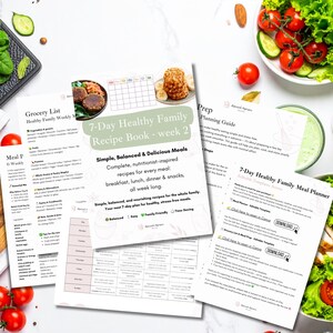 May include: A collection of printed recipe and meal planning guides. The main guide is titled "7-Day Healthy Family Recipe Book - week 2" with text describing simple, balanced meals. Fresh vegetables and prepared food are arranged around the guides.