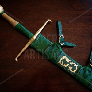 May include: A sword with a gold-colored pommel and crossguard, featuring a green leather-wrapped grip and a matching green scabbard. The scabbard is adorned with gold-colored filigree patterns and includes integrated leather straps with buckles.