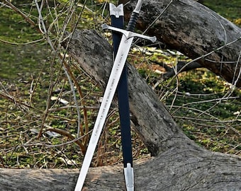 May include: A silver-toned metal sword with a cross-shaped guard and a black-wrapped handle, featuring an engraved star symbol near the hilt and runic-style inscriptions along the blade, accompanied by a matching black scabbard with silver accents.