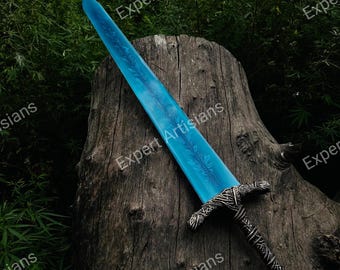 Könnte beinhalten: Ein Fantasy-Schwert mit einer hellblauen Klinge und aufwendigen floralen Designs. Der Knauf und der Griff sind mit silberfarbenem Metall verziert. Das Schwert liegt auf einer verwitterten Holzoberfläche, mit dem Text "Expert Artisians".