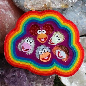 May include: A rainbow-coloured resin mould with six different character faces. The faces are all different colours and have different expressions. The mould is perfect for making resin crafts.