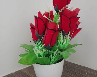 Rosas rojas vibrantes en una maceta de cerámica blanca