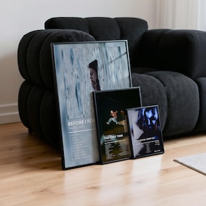 May include: Three framed art prints leaning against a black sofa. The largest print features a woman's face with the text "BEFORE I FOR". The middle print says "THE FIRST TIME". The smallest print says "PICK LOVE 3> OVER YOU".