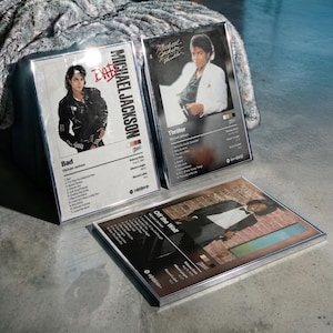 Può includere: Tre stampe artistiche incorniciate di album con Michael Jackson. La copertina dell'album "Bad" mostra Jackson con una giacca nera. La copertina dell'album "Thriller" mostra Jackson con un abito bianco. La copertina dell'album "Off the Wall" mostra Jackson con un abito.