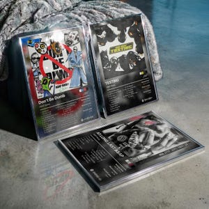 Puede incluir: Tres impresiones enmarcadas de arte de álbum. La impresión superior izquierda presenta ilustraciones coloridas con el texto "Don't Be Dumb" y "ASAP Rocky". La impresión superior derecha muestra el álbum "Testing" de ASAP Rocky. La impresión inferior es en blanco y negro.