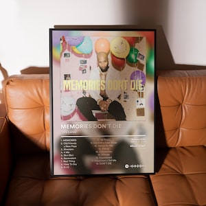 May include: A framed poster featuring the album art for "Memories Don't Die" by Tory Lanez. The artwork includes a photo of the artist, balloons, and the album's tracklist. The poster is displayed on a brown leather couch.