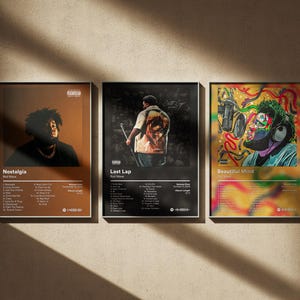 May include: Three framed music album art prints. The prints feature album covers with the artist's image and track listings. The album titles are "Nostalgia", "Last Lap", and "Beautiful Mind". The prints are in black frames.