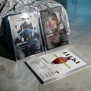 May include: Three framed music album posters featuring Lucki's Almost There, Days B4 III, and Freewave 3. Each rectangular print displays the album cover art, tracklist, release date, and record label information in a clean, organized layout.