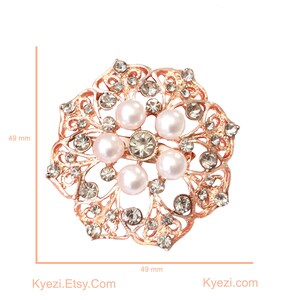May include: A rose gold brooch with a floral design, featuring faux pearls and clear crystals. The brooch is approximately 49 mm in diameter. The text "Kyezi Design & Craft" and "Kyezi.Etsy.Com" are visible.
