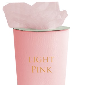 Może przedstawiać: Rolka jasnoróżowej tkaniny tiulowej. Tkanina znajduje się na białym kartonowym tubusie. Na tkaninie nadrukowany jest tekst "LIGHT PINK".