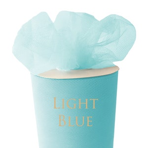 Może przedstawiać: Rolka jasnoniebieskiego tiulu. Tkanina jest owinięta wokół kartonowego tuby. Tekst "LIGHT BLUE" jest nadrukowany na tubie.