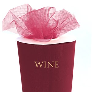 Może przedstawiać: Rolka tiulu w kolorze wina. Tkanina jest owinięta wokół kartonowego tuby. Tekst "WINE" jest nadrukowany na tubie.