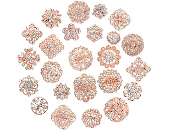 May include: A collection of 25 rose gold brooches with clear rhinestone embellishments. The brooches are arranged in a circle on a white background. The brooches are all different shapes and sizes, but they all have a similar design.  Kyezi Design & Craft.