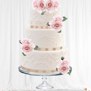 May include: A three-tiered white wedding cake with detailed icing, decorated with pink roses and gold ribbon. The cake is displayed on a clear glass stand. The cake is ideal for a wedding or celebration, with a classic design.