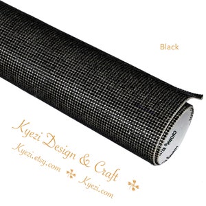 May include: A roll of black adhesive-backed rhinestone sheet. The sheet is covered in small, black rhinestones. The sheet is rolled up and the adhesive side is visible.