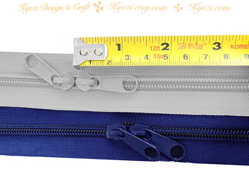 May include: Two zippers, one gray and one navy blue, are laid out side-by-side. A yellow measuring tape is placed above the zippers, showing a measurement of 2 inches.