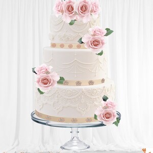 May include: A three-tiered white wedding cake with intricate lace-like frosting details and adorned with pink roses and green leaves. The cake features gold ribbon accents with sparkling embellishments and sits on a clear glass cake stand.