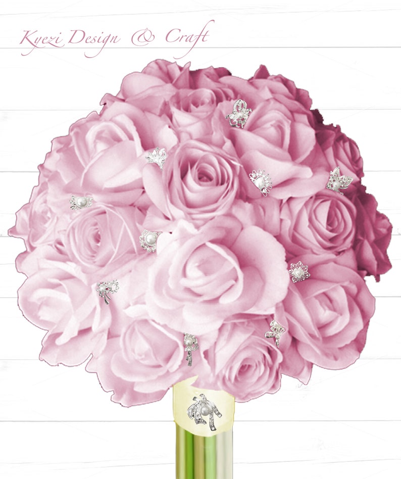 May include: A bouquet of pink roses with pearl and rhinestone embellishments. The roses are arranged in a circular shape and are held together with a green stem.