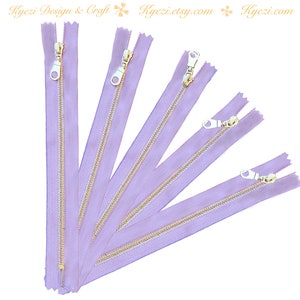 Può includere: Diverse cerniere color lavanda con tiretti in metallo dorato disposte su sfondo bianco. Le cerniere sono di lunghezze variabili, la più lunga in alto. Il testo "Kyezi Design & Craft" e "Kyezi.etsy.com" è visibile.