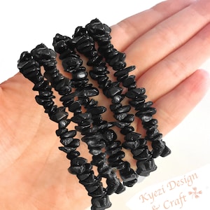 May include: Black chip stone bracelets, made with natural black chips. The bracelets are stacked on top of each other, showing the texture of the chips.
