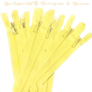 May include: A bundle of 7 yellow zippers with gold pulls. The zippers are all the same length and are arranged in a fan shape.