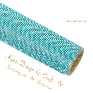 May include: A roll of aquamarine blue rhinestone sheet. The sheet is covered in small, sparkling rhinestones. The text "Kyezi Design & Craft" and "Kyezi.etsy.com" is visible on the bottom left corner of the image.
