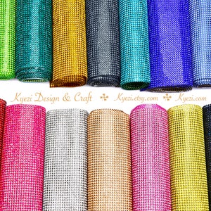 May include: Rolls of sparkly rhinestone mesh fabric in various colors, including teal, gold, black, turquoise, blue, pink, silver, gold, copper, and hot pink.  The fabric is ideal for crafting and decorating.