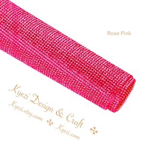 May include: A roll of rose pink rhinestone mesh fabric. The fabric is made of small, sparkling rhinestones that are sewn together in a grid pattern. The fabric is perfect for adding a touch of glamour to any project.