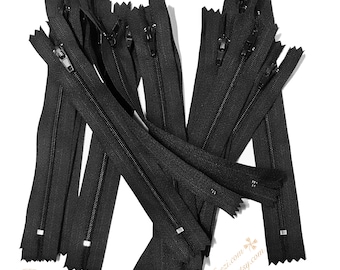 May include: A bulk pack of 15 black zipper closures, each measuring approximately 12.7 cm in length. The zippers are arranged in a pile, with the zipper teeth facing up.