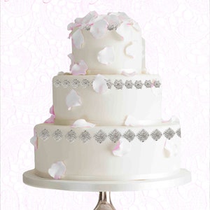 May include: A three-tiered white wedding cake decorated with silver embellishments and pink rose petals.